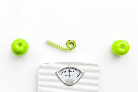 Bathroom scale, measuring tape and apples on white background top view copyspace