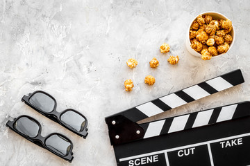 Watching film in the cinema. Clapperboard, glasses and popcorn on grey background top view copyspace