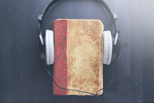 book cover and headphones over dark table