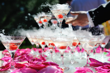 A slide of champagne with dry ice and smoke at the solemn event. Pyramid of glasses with alcohol and cherries.