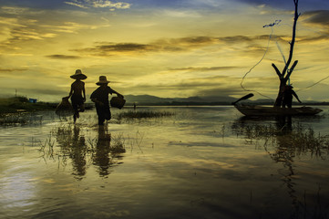 Fototapeta premium Early morning fishing boat ,Fishermen and kid fishing in the early morning golden light on the boat,Cloundy sky and water background.