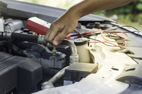 Auto mechanic uses hand of technician checking or fixing engine of in a car.