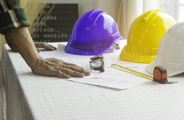 Man of engineers writing at a blueprint for construction on the table.