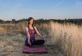 Fototapeta na wymiar Young woman meditating with closed eyes, beautiful scenery 