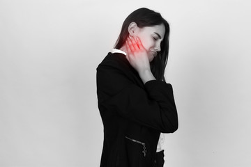 Portrait of a pretty young businesswoman holding her neck in pain and discomfort. Black and white with red accent