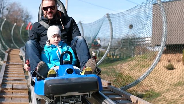 Father and son enjoying while riding forest roller coaster