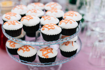 Cupcakes with initials of the bride and groom on a two-level stand at a wedding