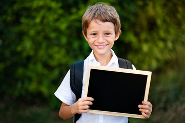 Cute caucasian school child hold a blank chalkboard for education conceptual