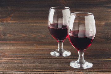 Two glasses of red wine on a brown wooden table. Alcoholic beverages.