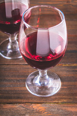 Two glasses of red wine on a brown wooden table. Alcoholic beverages.