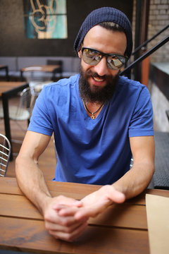 Bearded man in sunglasses touching his hand