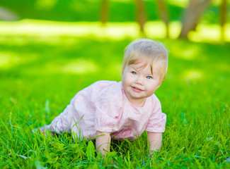 Happy baby crawling on green grass