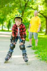 Portrait of a boy in a protective helmet and protective pads for roller skating on the background of his father