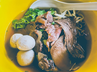 Beef noodle soup in a yellow bowl, close up