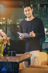 young asian freelance man standing with smiling face in home office happiness emotion