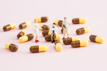 Miniature doctor and nurse posing in a group of pills