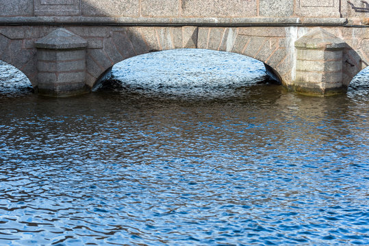 Water surface and arched supports of the stone bridge