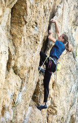 adult woman rock climber. rock climber climbs on a rocky wall. woman makes hard move