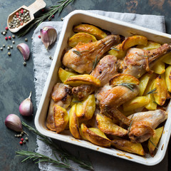 Homemade Roast chicken legs and wings with potato, rosemary and garlic. Rustic style, top view