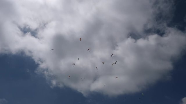 A lot of paragliders flying in the clouds. Amazing view on blue sky. recreational and competitive adventure sport.