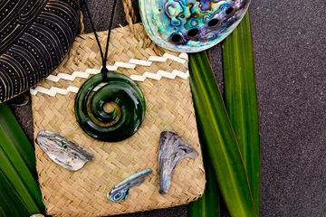 Fototapeten New Zealand - Maori themed objects - greenstone jade pendant on woven kite flax bag with shell pieces © CreativeFire