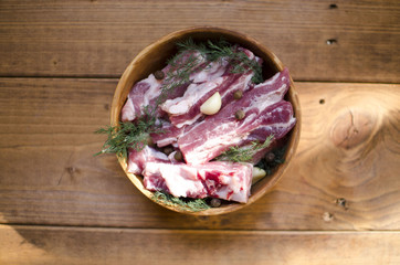 Pork meat in a clay bowl. Raw pork ribs with allspice, garlic and dill. Preparation for cooking