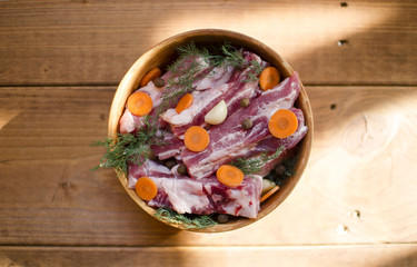 Pork meat in a clay bowl. Raw pork ribs with allspice, carrot, garlic and dill. Preparation for cooking