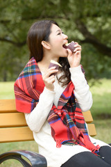 秋の公園で焼き芋を食べる女性