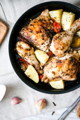 Stewed chicken in herbs in a frying pan, close-up, top view.