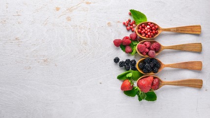 Assortment of berries. Raspberries, blackberries, strawberries, cranberries. On a wooden background. Top view. Free space for text.