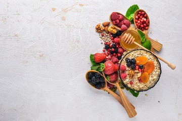 Fototapeta na wymiar Healthy food. Fresh wild berries, copper, nuts, oatmeal, dried fruits and seeds. On a wooden background. Top view. Free space for text.