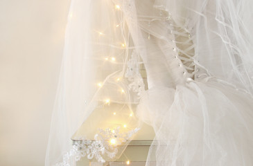 Beautiful white wedding dress and veil on chair with gold garland lights
