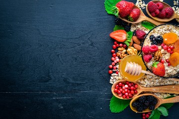 Healthy food. Fresh wild berries, copper, nuts, oatmeal, dried fruits and seeds. On a wooden background. Top view. Free space for text.