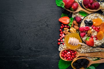 Healthy food. Fresh wild berries, copper, nuts, oatmeal, dried fruits and seeds. On a wooden background. Top view. Free space for text.