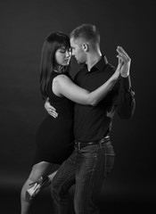 Young couple dancing on a dark background