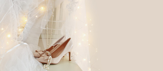 Beautiful white wedding dress and veil on chair with gold garland lights