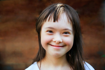Cute smiling down syndrome girl on the brown background - 168966857