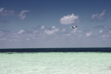 Airplane flying above tropical sea