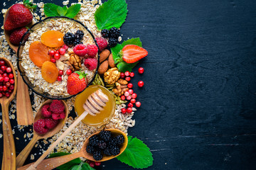 Obraz na płótnie Canvas Healthy food. Fresh wild berries, copper, nuts, oatmeal, dried fruits and seeds. On a wooden background. Top view. Free space for text.