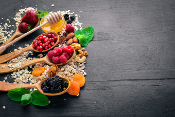 Healthy food. Fresh wild berries, copper, nuts, oatmeal, dried fruits and seeds. On a wooden background. Top view. Free space for text.