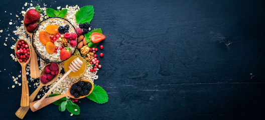 Healthy food. Fresh wild berries, copper, nuts, oatmeal, dried fruits and seeds. On a wooden...