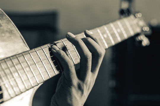close up on hand playing guitar on black and white tone