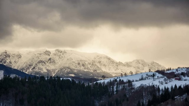 Landscape of the Rucar-Bran Corridor in winter at sunset. Transylvania, Romania.	Isolated houses in foreground and dynamic clouds over mountains in background. 4k timelapse.