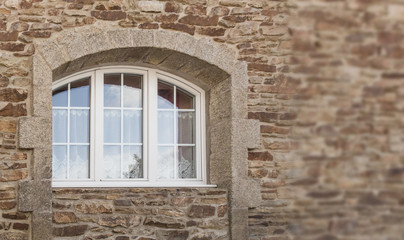 Schönes Bogenfenster aus weißem PVC mit 3 Flügeln in Fassade aus Naturstein in Granit -...