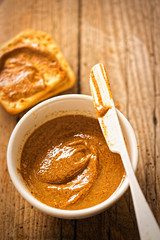 Almond butter in bowl with crackers on wooden table 