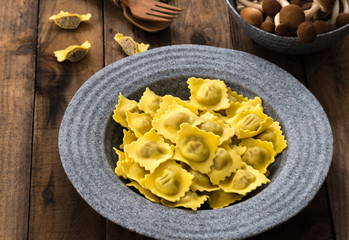 Plate of ravioli with mushroom on wood table

