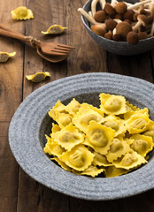 Plate of ravioli with mushroom on wood table

