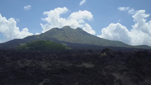 AERIAL: Flying above rough stony black lava terrain and grey ashy volcanic soil at the toot of Mount Batur towards the peak of the mountain range. Dramatic landscape at Kintamani volcano crater, Bali