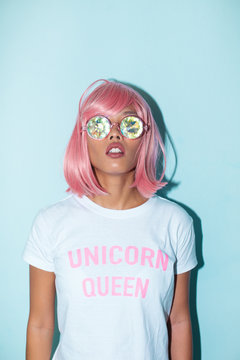 Asian pink hair woman portrait with kaleidoscope glasses and unicorn queen shirt