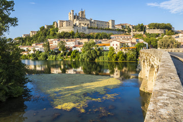 Fototapeta na wymiar Views at sunset of the French city of Beziers, with trees, the river Orb, and the 13th-century Cathedral of Saint Nazaire in the background